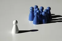 Leadership feature image of one white chess piece facing a group of blue chess pieces.