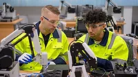 Two technicians work with robotic arm. Advance technology and industry concept.