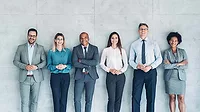 Group of business persons standing against a wall.