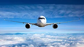 Passenger airplane flying with a blue sky and clouds in the background.