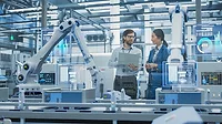 Managers having a discussion while automated robot arms work and AI computer vision scans conveyor line.