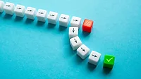 Small white dice with think black arrows, one rad with a white scribble and one green with a checkmark.