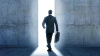 Businessman walking into bright light from inside building. Businessman walking into bright light from inside building.