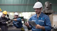 Group of factory workers checking or maintaining CNC machine in industry factory.