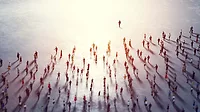 Overhead view of a community of people following a leader towards a bright light.