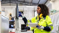 Female worker operating cutting machine.