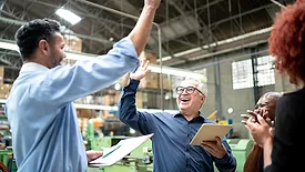 Coworkers celebrating some good news in a factory.