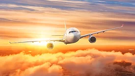 Airplane above the clouds in the sky at sunrise.