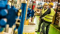 Industrial workers working on equipment in a factory.