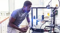 African-American male engineer using a 3D printer in the laboratory while studying a product prototype, and technology.