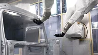 Painting car using robotic machine in production.