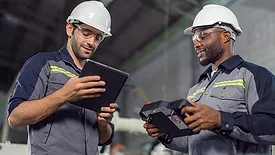 Two Industry engineers stand and discuss work in the factory workshop.