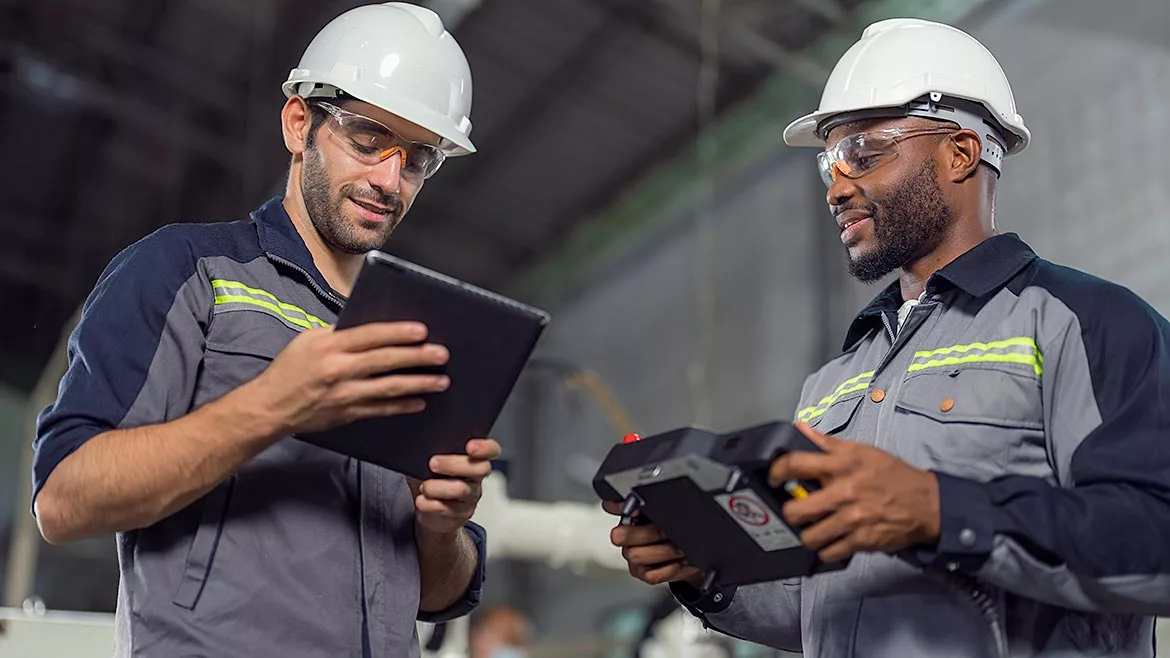 Two Industry engineers stand and discuss work in the factory workshop.