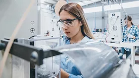 Female industrial worker working with manufacturing equipment in a factory.
