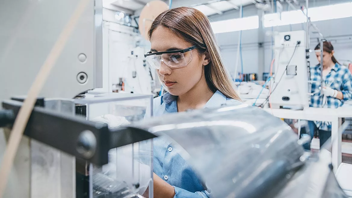 Female industrial worker working with manufacturing equipment in a factory.