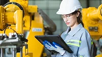 Engineer woman working in advance machine factory Female worker engineering staff work checking robot arm in assembly plant with tablet.