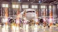 Large-scale inspection of all aircraft systems in the aircraft hangar Large-scale inspection of all aircraft systems in the aircraft hangar by worker mechanics and other specialists. Bright light streaming outside from the garage door.