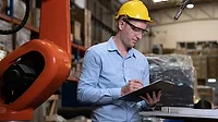 Engineer working in a welding factory checking robotic arm and welding head.