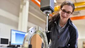 Woman working in quality control, measuring a workpiece.