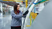 Female maintenance engineer examining car chassis.
