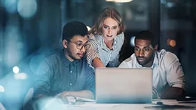 Cropped shot of three young businesspeople working together on a laptop in their office late at night.