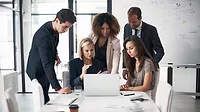 A group of business people looking at a laptop during a conference.