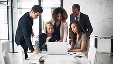 A group of business people looking at a laptop during a conference.