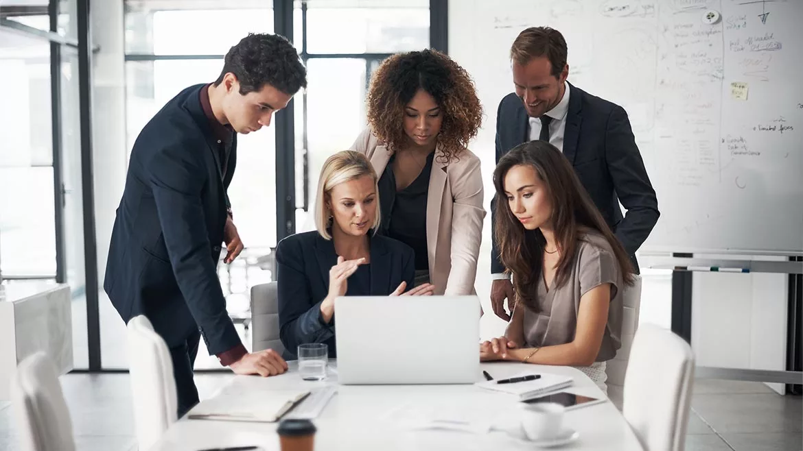 A group of business people looking at a laptop during a conference.