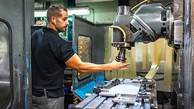 Worker using milling machine in a CNC factory.