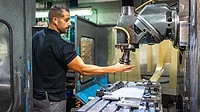 Worker using milling machine in a CNC factory.