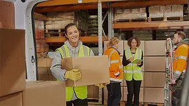 Female warehouse worker, other workers in the background.
