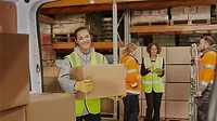 Female warehouse worker, other workers in the background.
