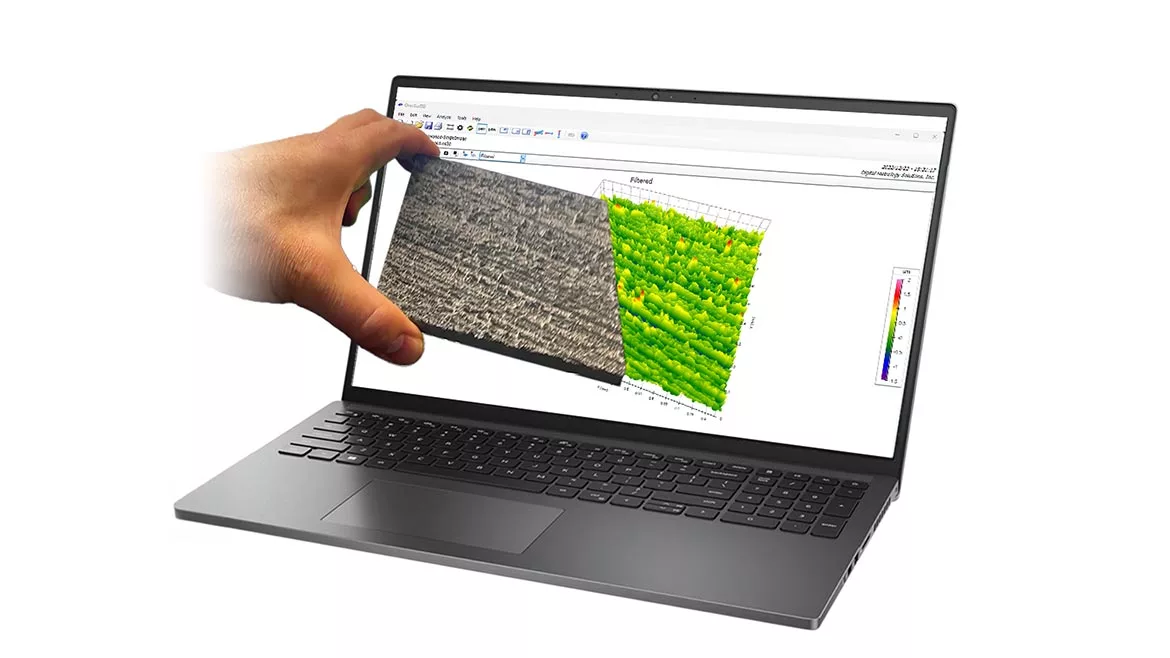 Hand holding material in front of laptop showing surface texture data.