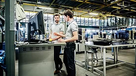 Two printing factory engineers working at a console together.