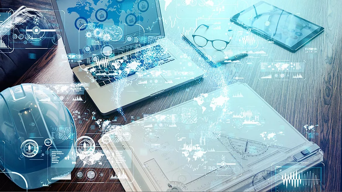 Industrial technology concept layed over a work desk with a laptop, hardhat, glasses, table, folder on top.