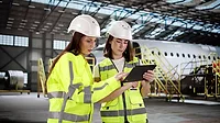 Two women with a tablet check an aircraft engine at the airport maintenance hangar Two women with a tablet check an aircraft engine at the airport maintenance hangar.