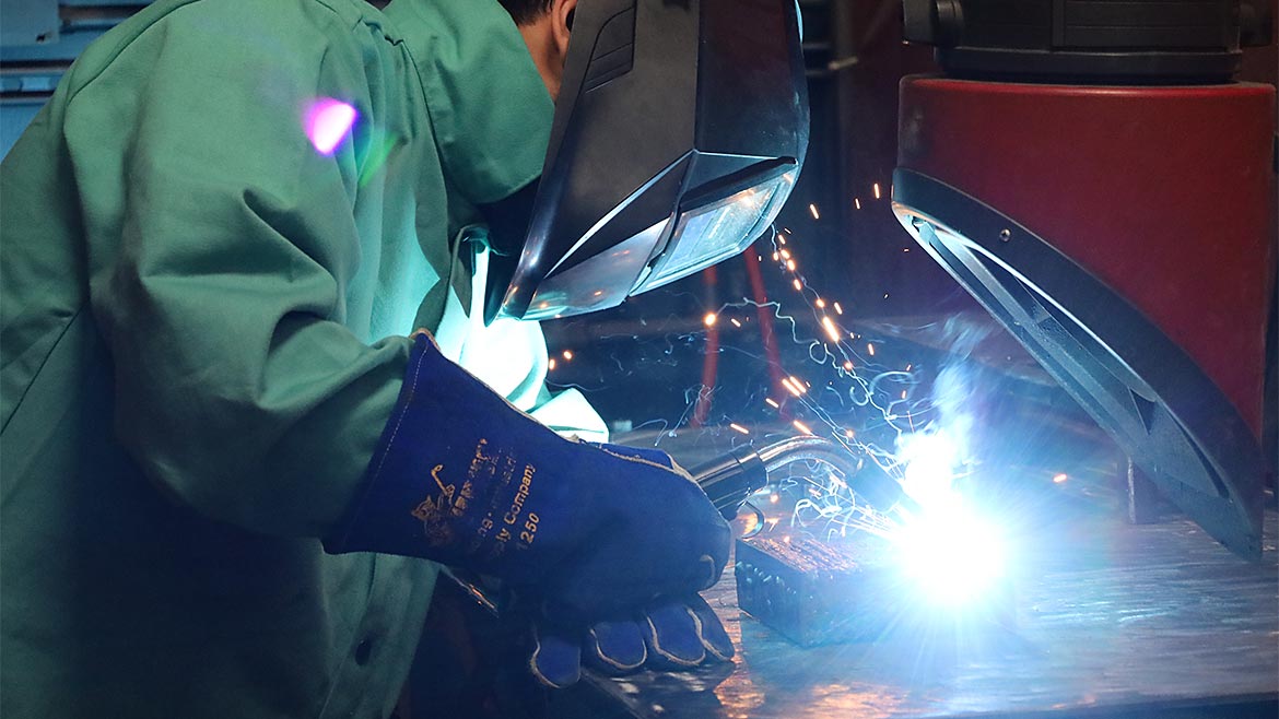 A close-up of a person in protective gear welding.