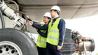 Asian man and woman engineers looking at a wheel of an airplane as part of an team that keeps airplanes maintained for safety.