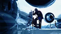 Flight engineer in silhouette inspecting an airplane.