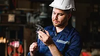 Professional male technician checking and repairing machinery.