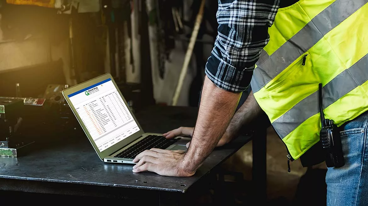 Worker wearing a safety vest looking at a laptop. Quality Control Module on the shop floor.
