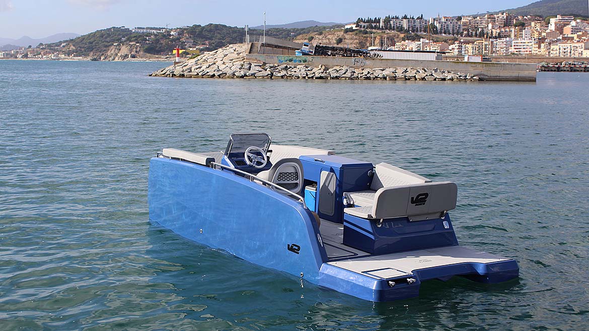 Boat in the water with hills and a town in the background.