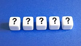 Five dice with question marks on them on a dark blue background.
