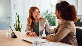 Businesswomen comforting colleague during meeting in office boardroom.