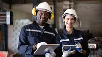 Two technicians engineers workers holding tablet checking and working together at factory.