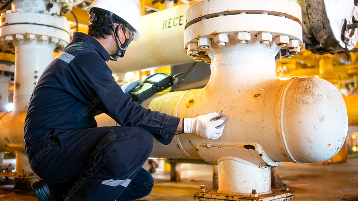 Inspecting pipes using ultrasonic NDT instruments at petrochemical facility.