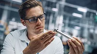 Close-up of a young engineer in glasses, working on manufacturing metal parts at a car assembly plant Close-up of a young engineer in glasses, working on manufacturing metal parts at a car assembly plant.