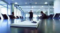 Three men in a boardroom, one man pointing. Focus on notepad Three men in a boardroom, one man pointing. Focus on notepad