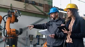 Female engineer manager and mechanic worker doing routine check-up in industrial factory.