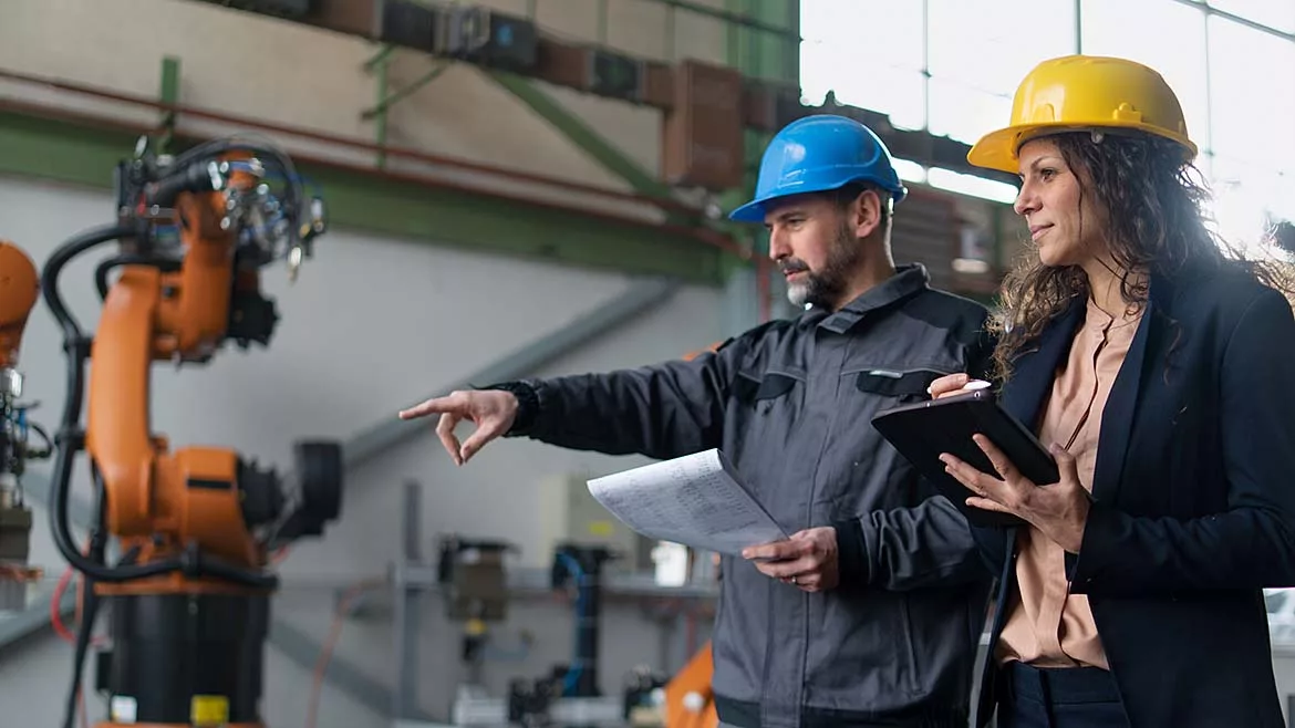 Female engineer manager and mechanic worker doing routine check-up in industrial factory.